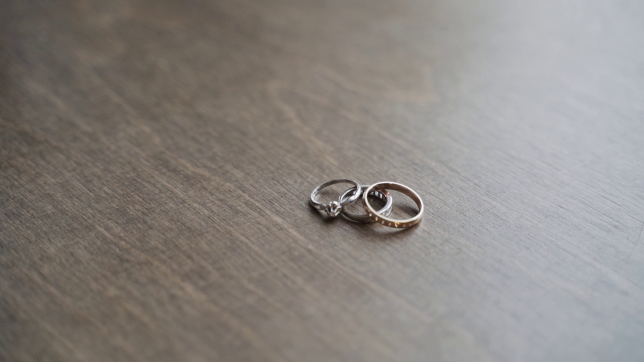桌上放着结婚戒指和订婚戒指。手从表面取下珠宝视频素材