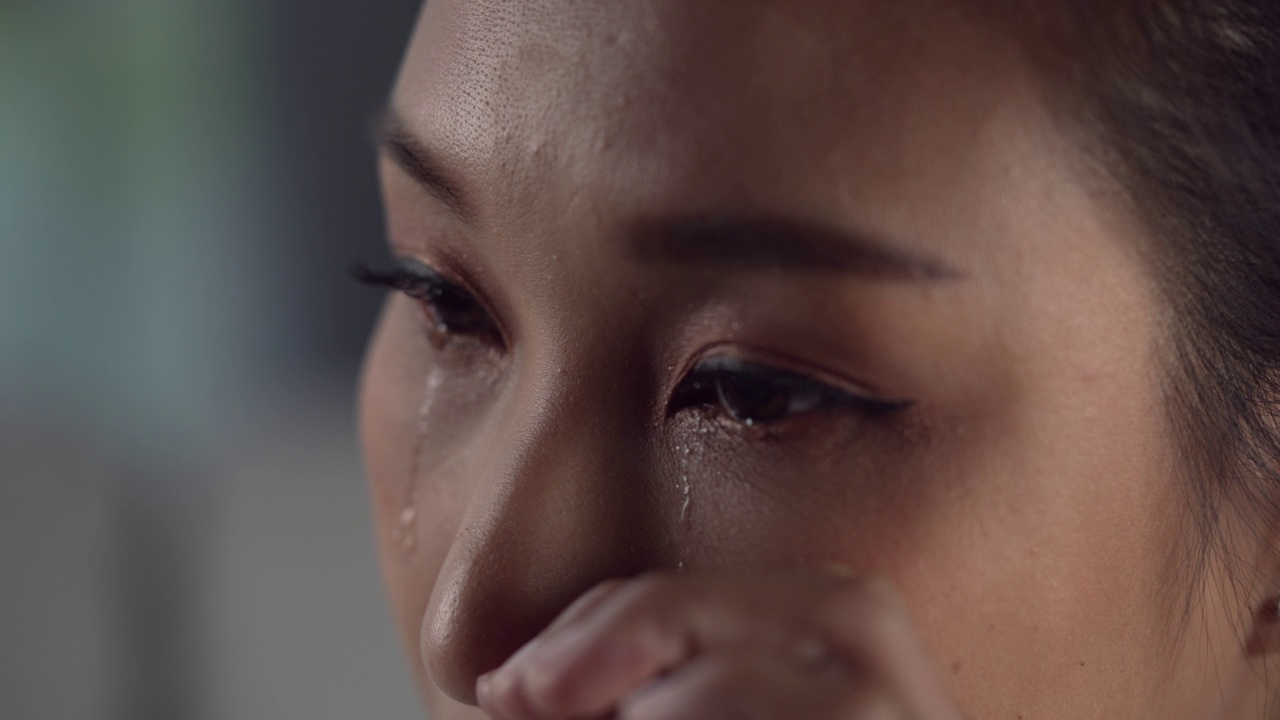 沮丧和沮丧的年轻亚洲女性哭泣的眼泪从她的眼睛，悲伤的亚洲女性感到沮丧，思考问题。视频素材