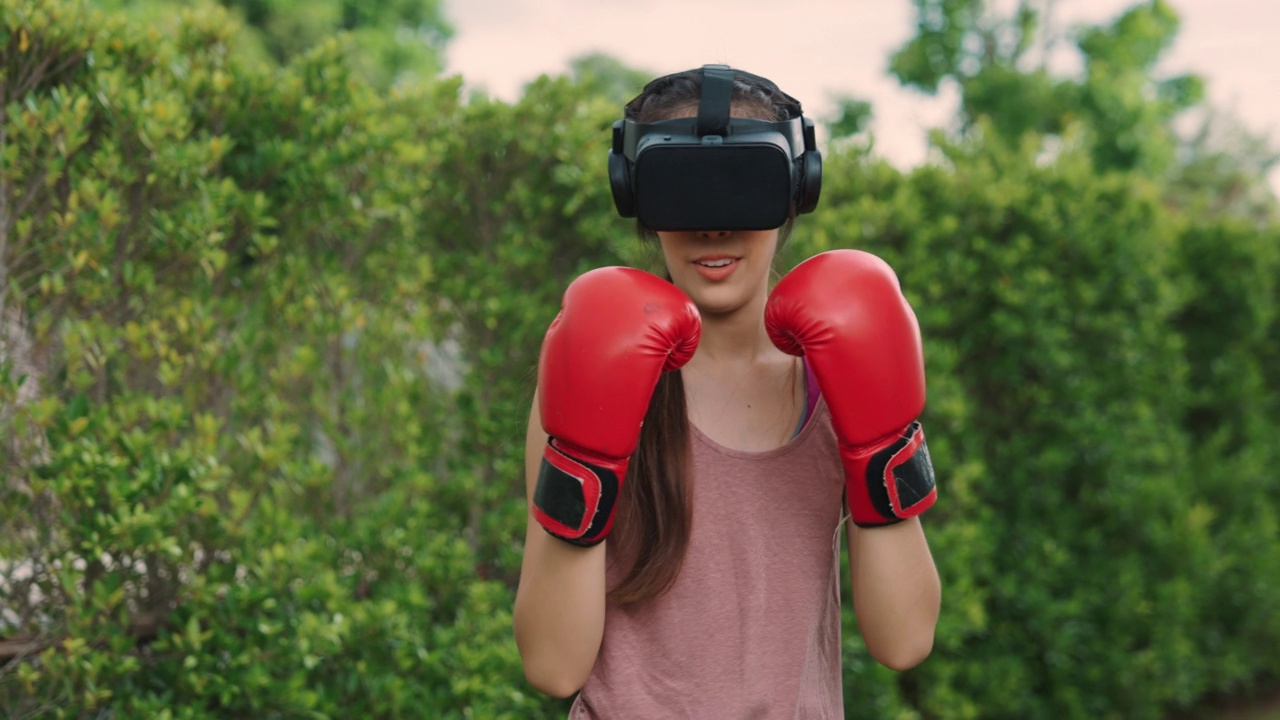 亚洲女性戴着虚拟现实头盔玩拳击运动视频素材