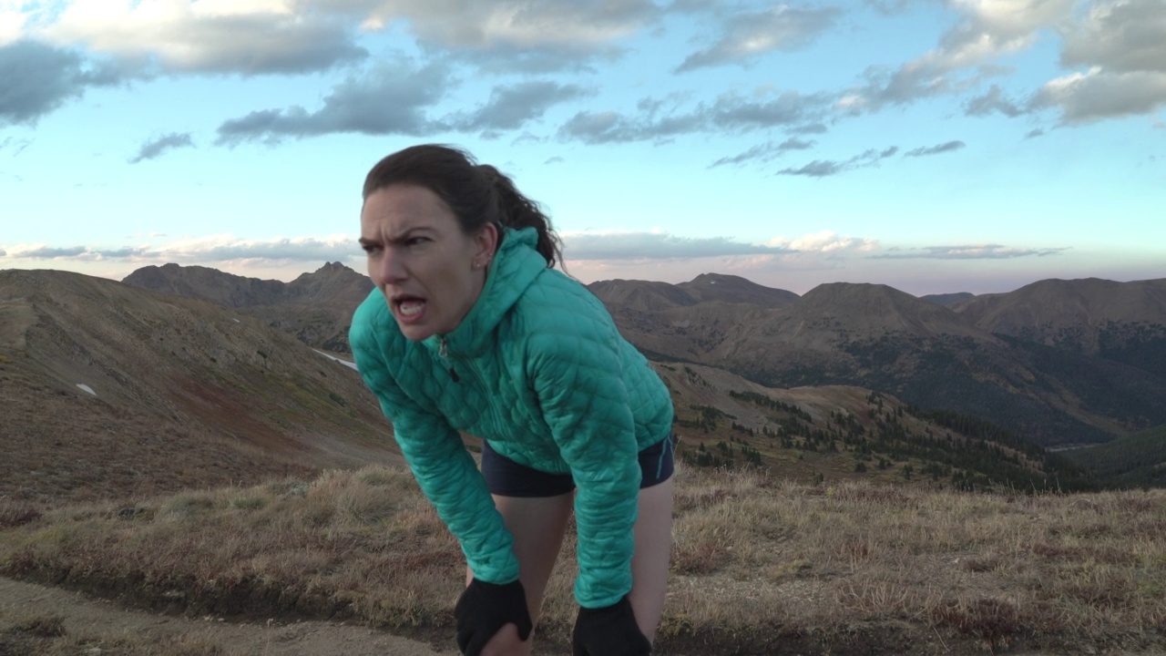 休息呼吸的女人在山中越野跑后喘不过气来。——慢动作视频素材