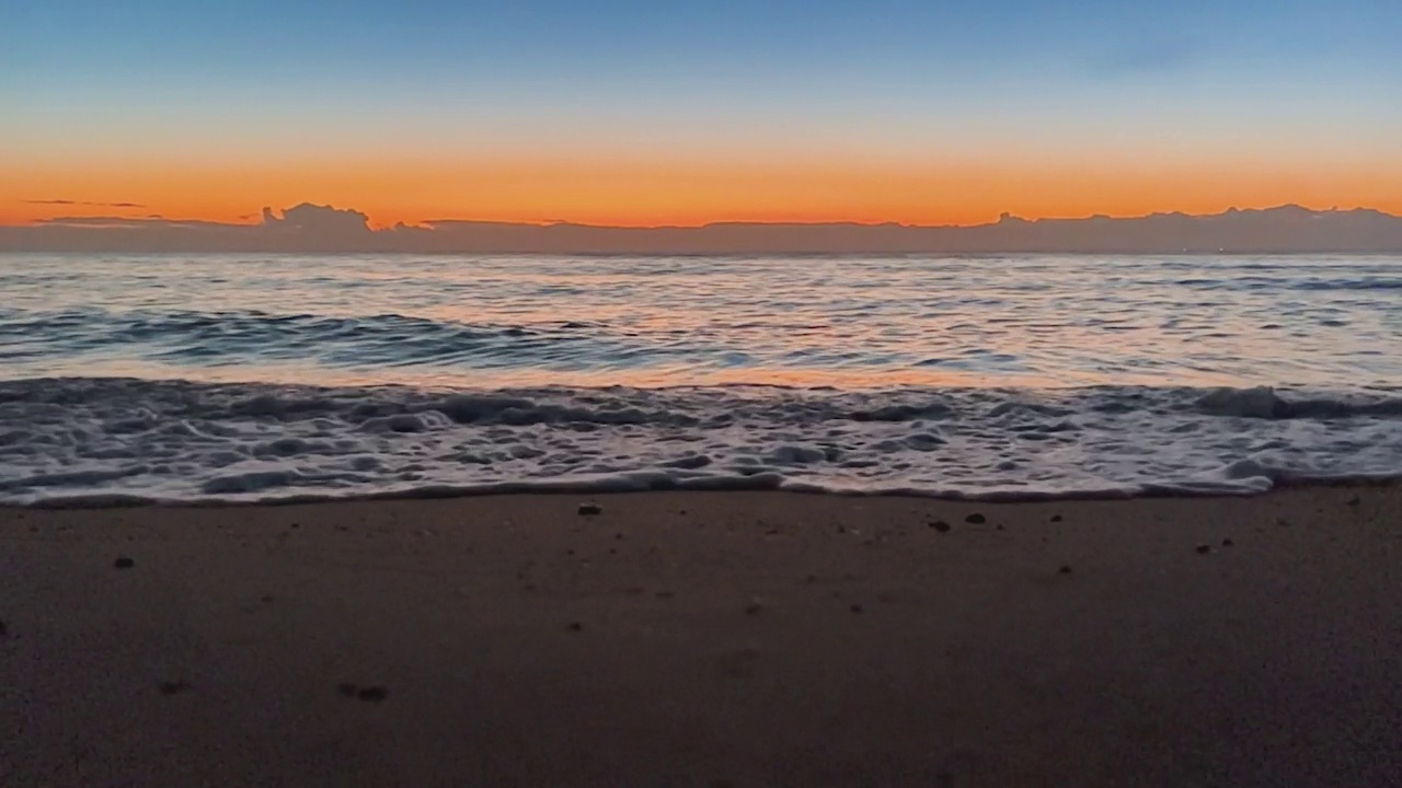 海浪在沙滩上与蓝天在清晨的日出视频素材