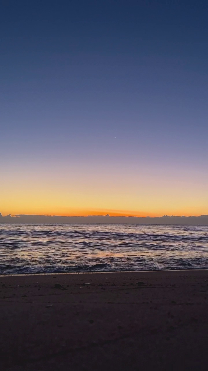 垂直比。海水波浪在沙滩上与蓝天在清晨的日出视频素材