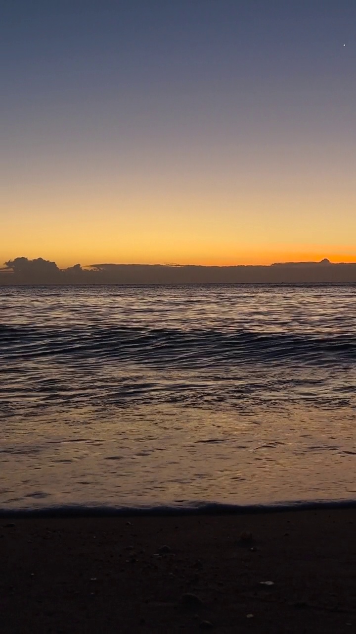 垂直比。海水波浪在沙滩上与蓝天在清晨的日出视频素材