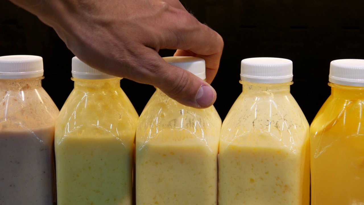 特写塑料瓶和天然水果酸奶和一个男性的手拿一个视频素材
