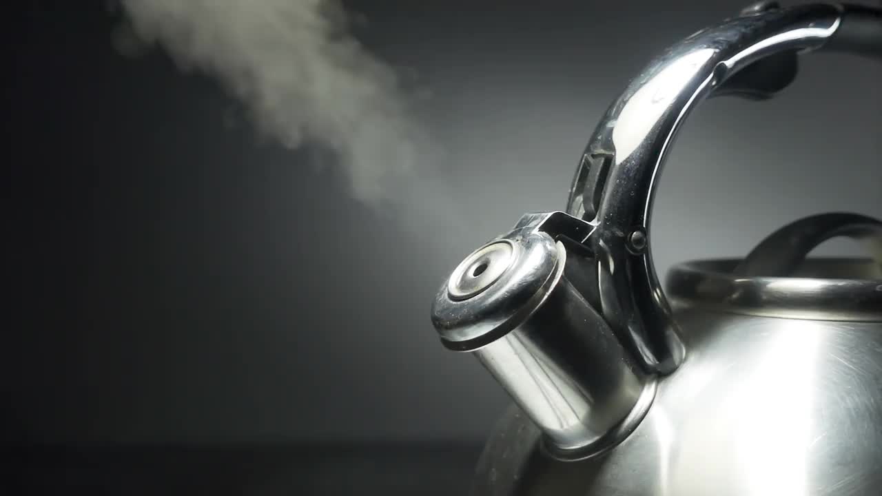 沸腾的钢银水壶与汽笛与蒸汽特写在黑色背景。4k原始慢动作视频60帧。视频下载