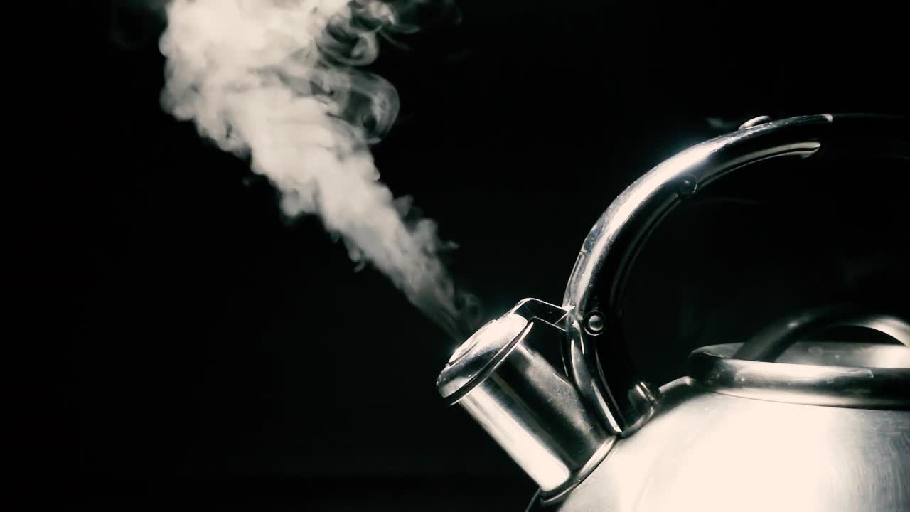 煮沸钢银水壶与汽笛与蒸汽特写在黑色背景。带有速度斜坡效果的4k原始慢动作视频。用高速电影摄影机拍摄的。视频素材