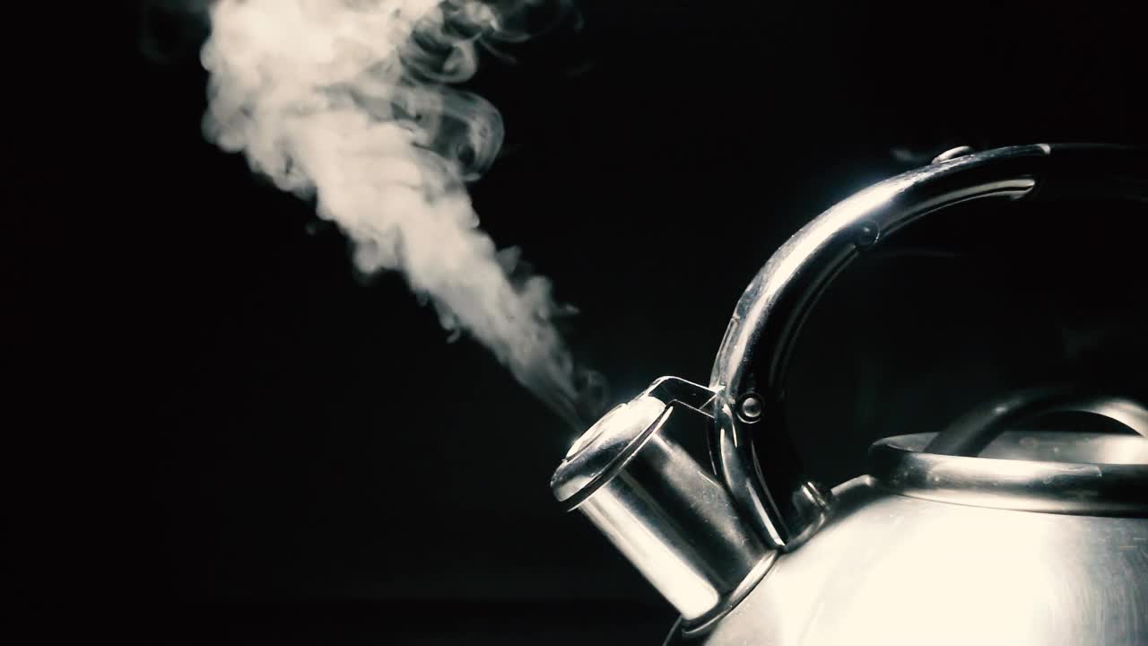 煮沸钢银水壶与汽笛与蒸汽特写在黑色背景。4k原始慢动作视频。视频素材