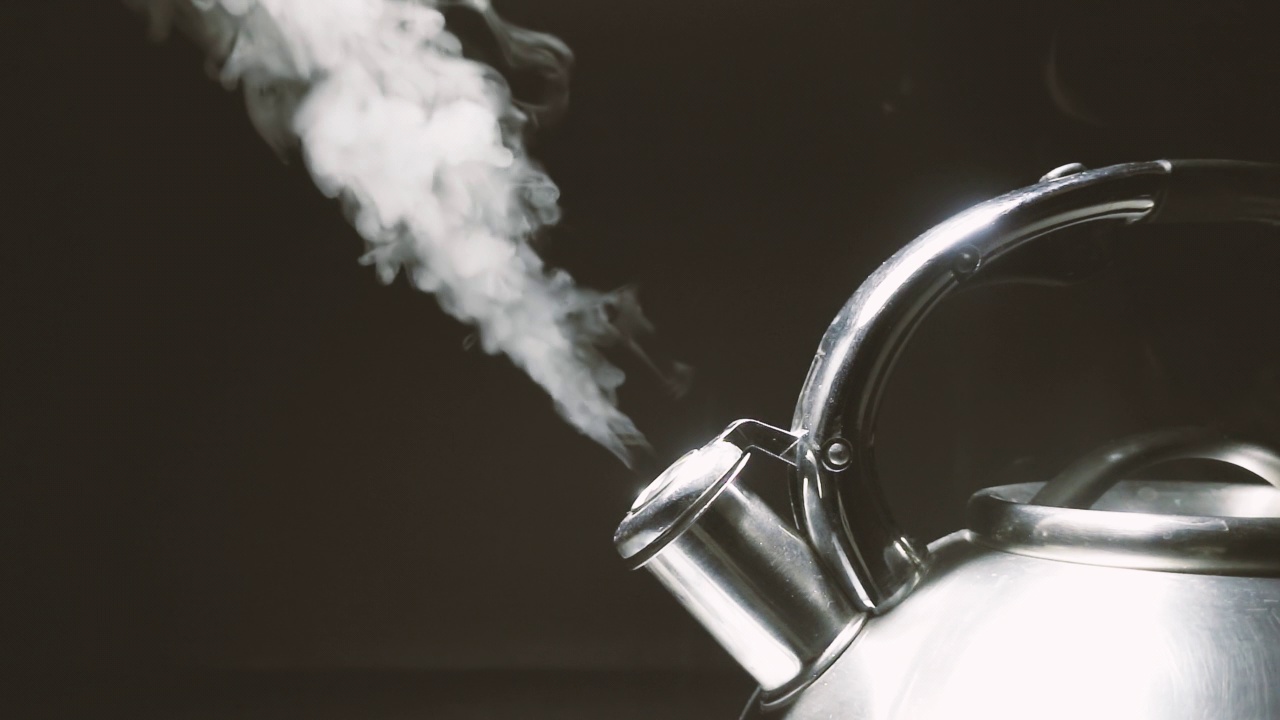 煮沸钢银水壶与汽笛与蒸汽特写在黑色背景。4k原始慢动作视频。视频素材