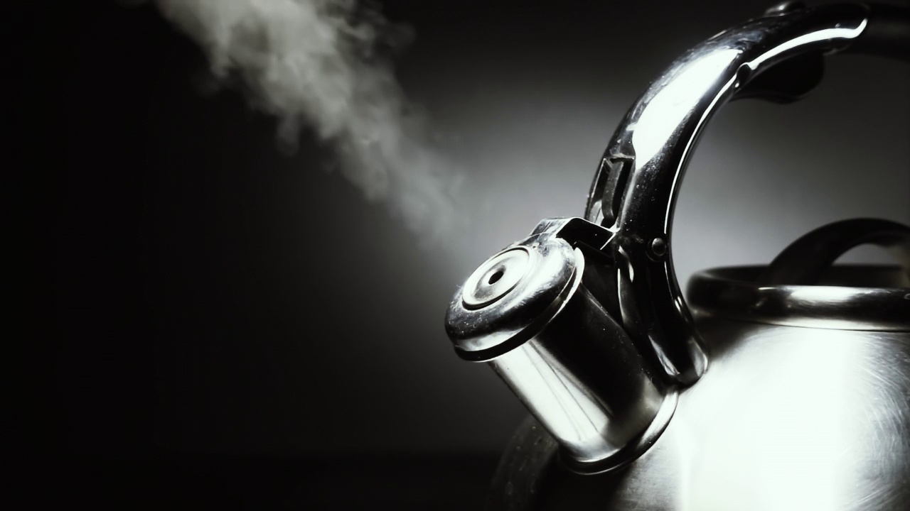 煮沸钢银水壶与汽笛与蒸汽特写在黑色背景。4k原始慢动作视频60帧/秒。视频素材