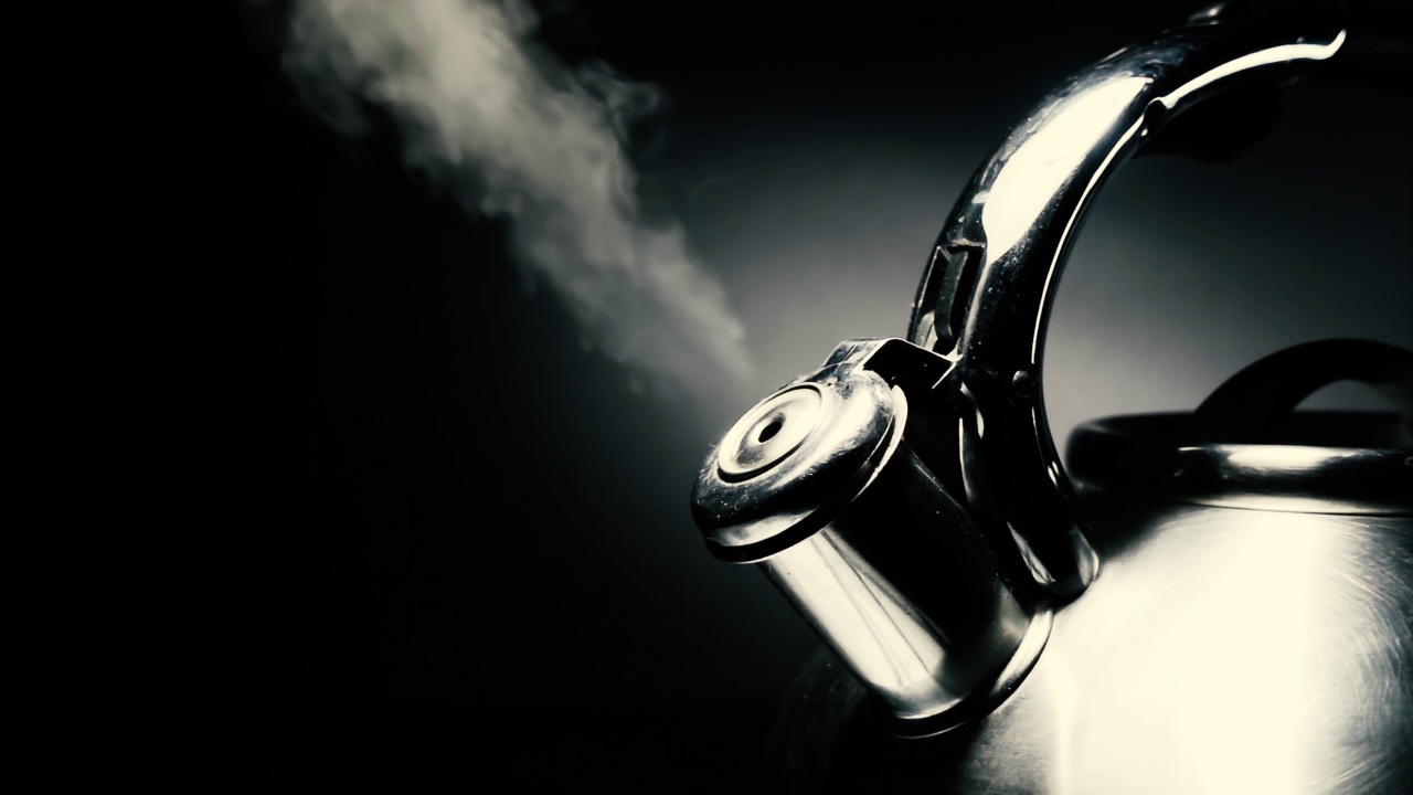 沸腾的钢银水壶与哨子蒸汽特写在黑色背景。4k原始慢动作视频60帧/秒。视频素材