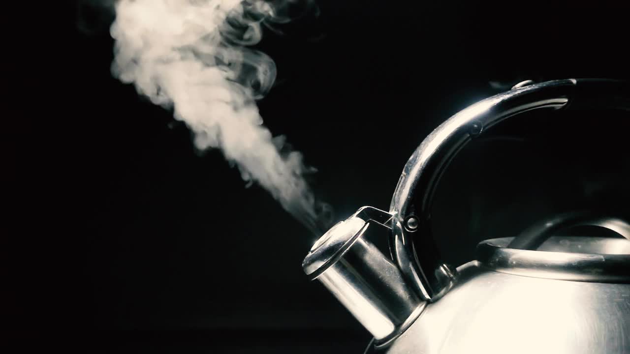 煮沸钢银水壶与汽笛与蒸汽特写在黑色背景。带有速度斜坡效果的4k原始慢动作视频。用高速电影摄影机拍摄的。视频素材