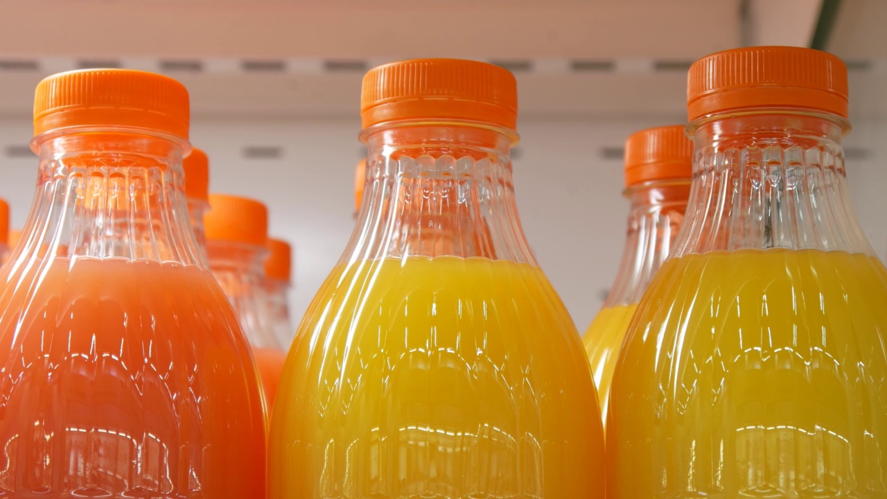 特写的许多塑料瓶不同的柑橘类果汁和一个男人的手拿一个视频素材
