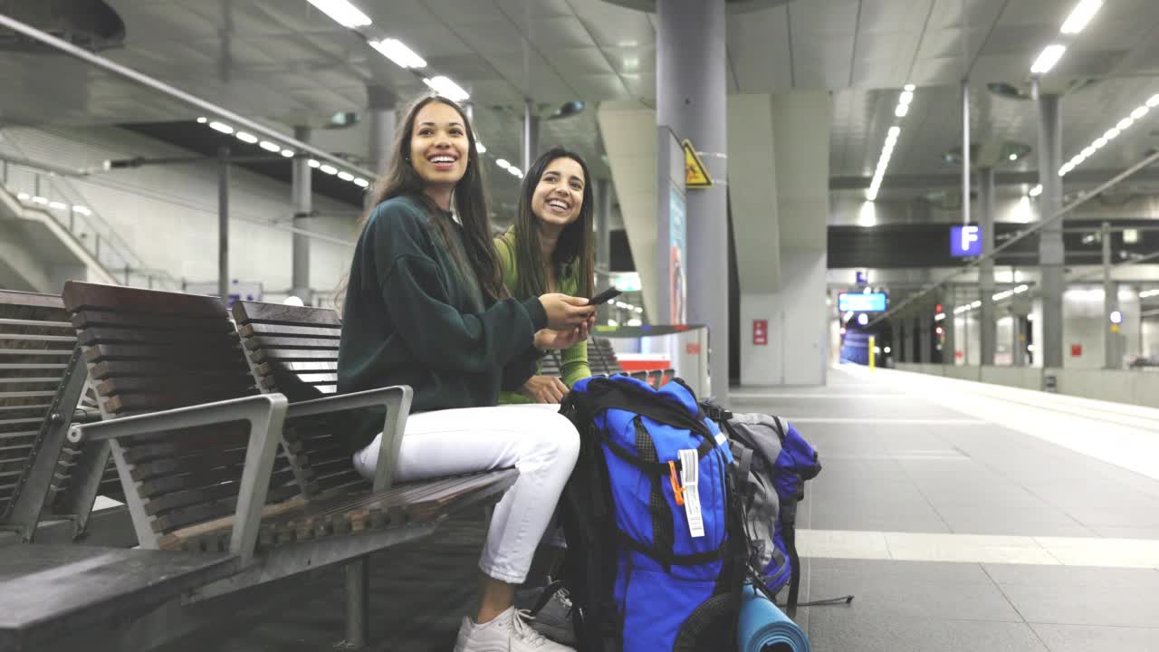 兩個女性朋友在車站等火車，用手機查火車時間視頻素材