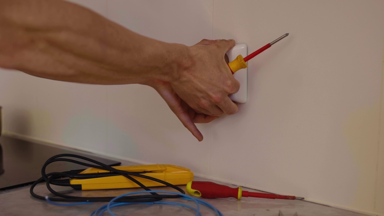 技术员用螺丝刀从家里的墙壁上拆卸电源插座视频下载