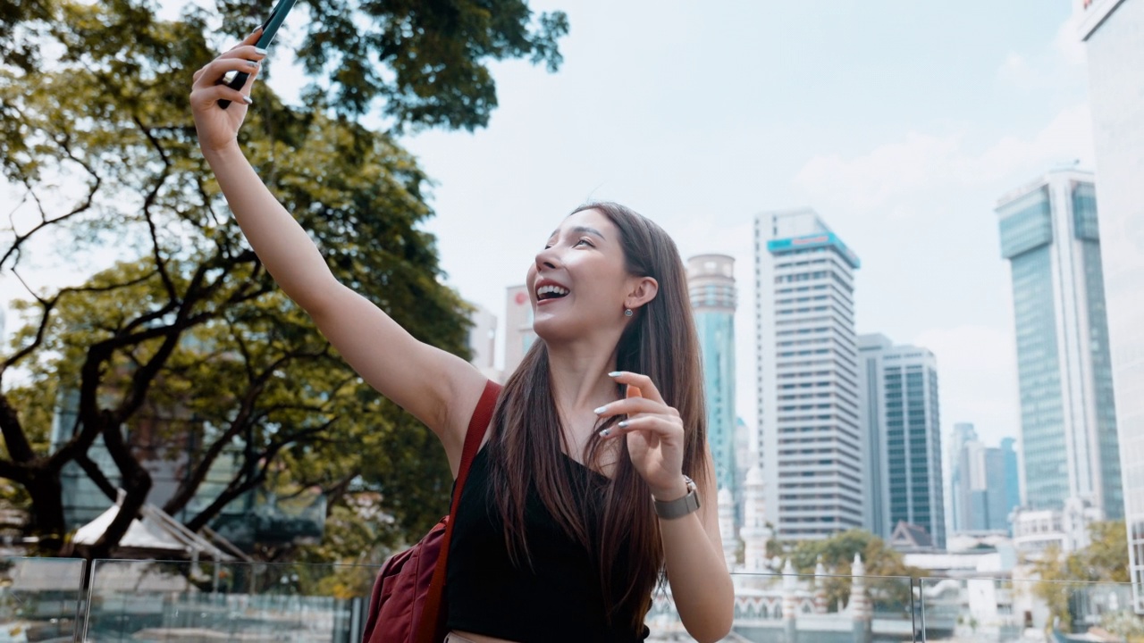一名亚洲女子在吉隆坡的Masjid Jamek瞭望点旅行时用智能手机拍照视频下载