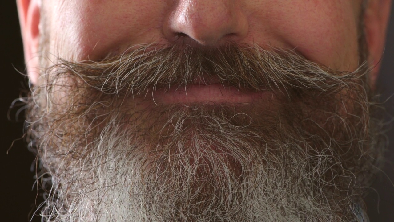 一个带着歪牙和浓密胡须的微笑男人的特写。一个成熟的、复古的、脸上带着大大的微笑的大胡子男人的细节。不刮胡子，留着胡子或胡须，牙齿染色视频下载