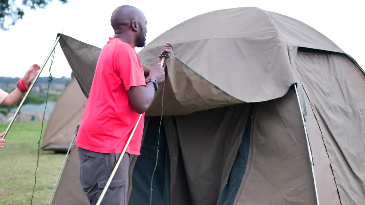 一名黑人男子和一名白人女孩助手为游客搭起帐篷露营视频素材