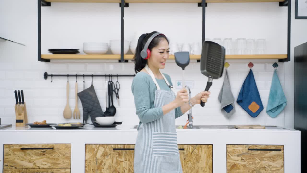 欢快的亚洲女人在厨房里跳舞视频下载