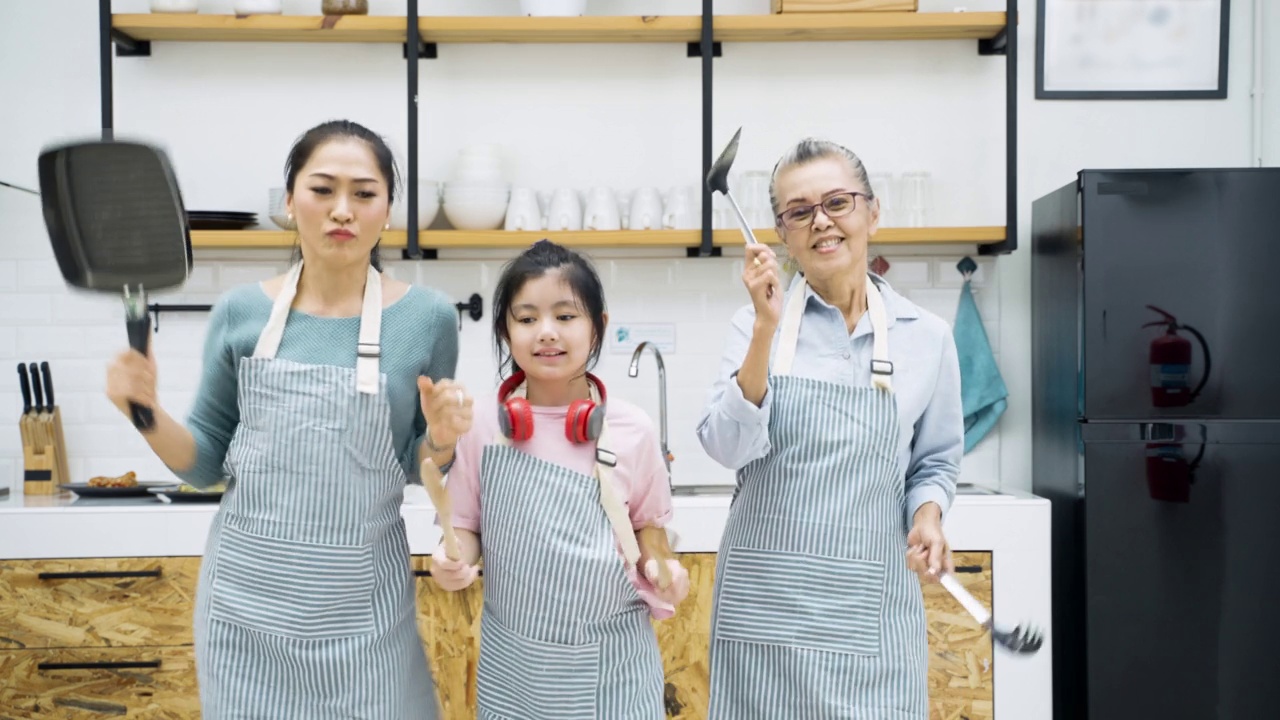 欢快的亚洲家庭在厨房准备食物时跳舞视频下载
