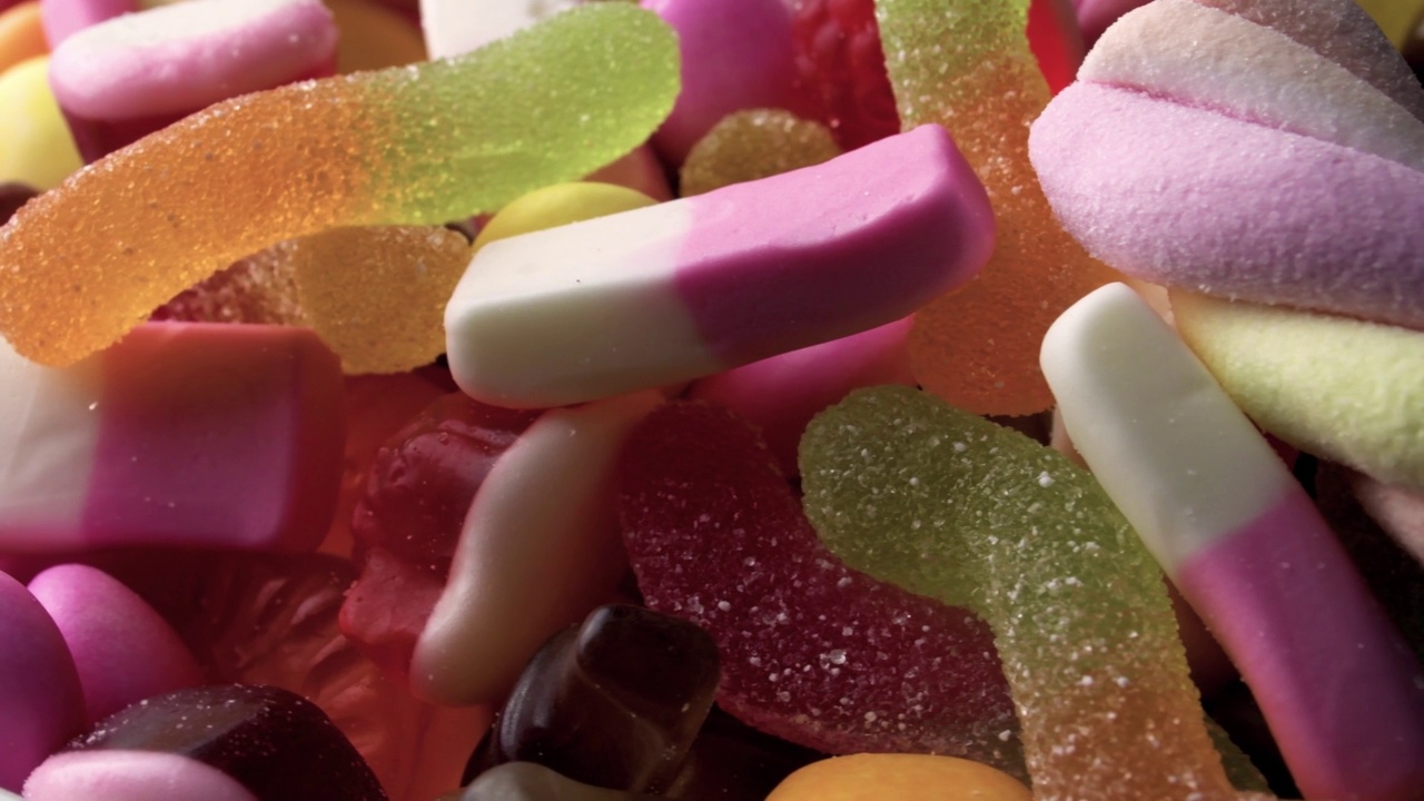 4k视频在30帧/秒的特写旋转组合堆美味的糖果概念甜不健康的糖果，鲜艳的糖果和孩子聚会的甜点视频下载