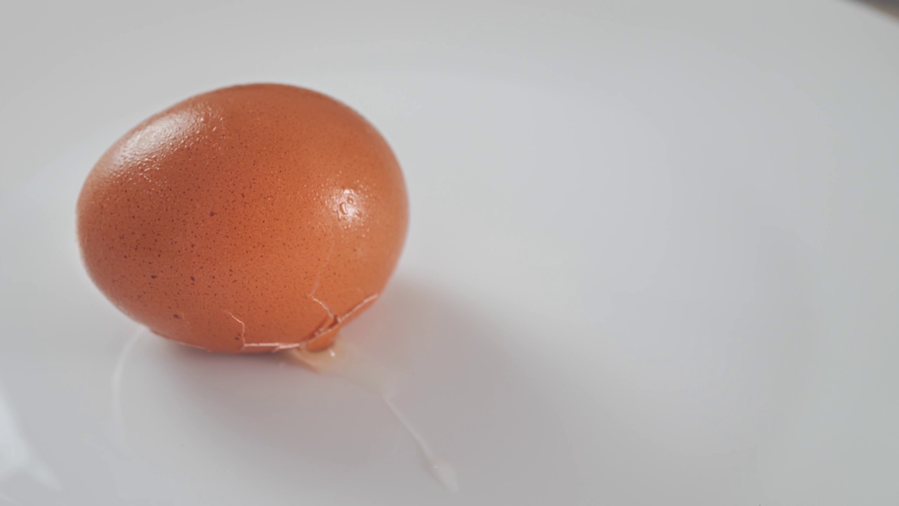 打碎的鸡蛋放在白色的桌子上。厨师打碎了鸡蛋。白色的鸡蛋掉在地上摔碎了。慢动作视频剪辑。鸡蛋掉下来摔碎了。视频下载
