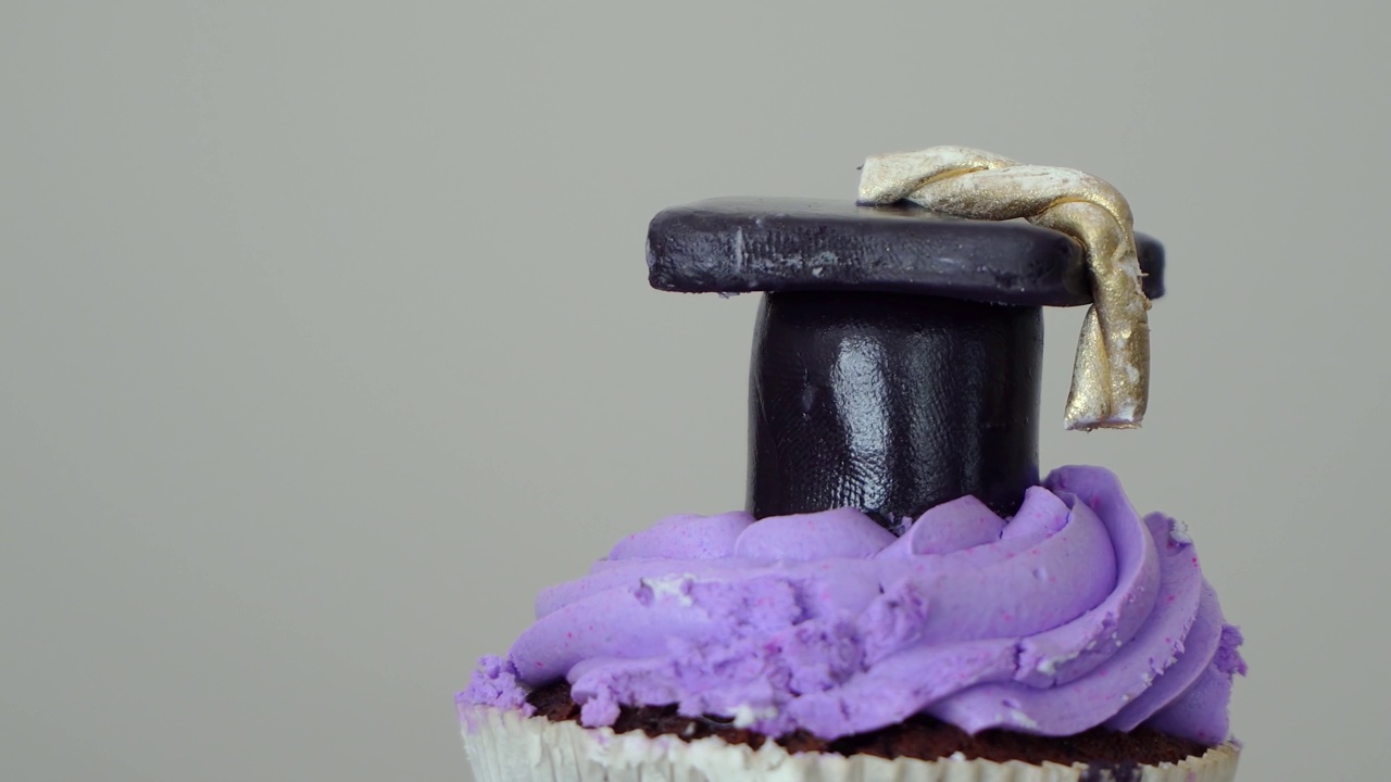 毕业派对巧克力纸杯蛋糕，上面有紫色和黑色的毕业帽视频下载