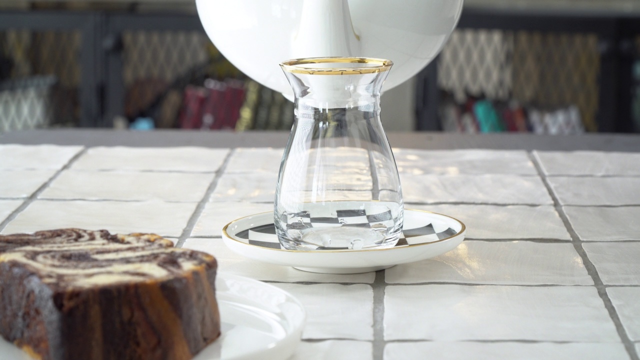 用现代土耳其玻璃杯倒土耳其茶，桌上放着大理石蛋糕视频素材
