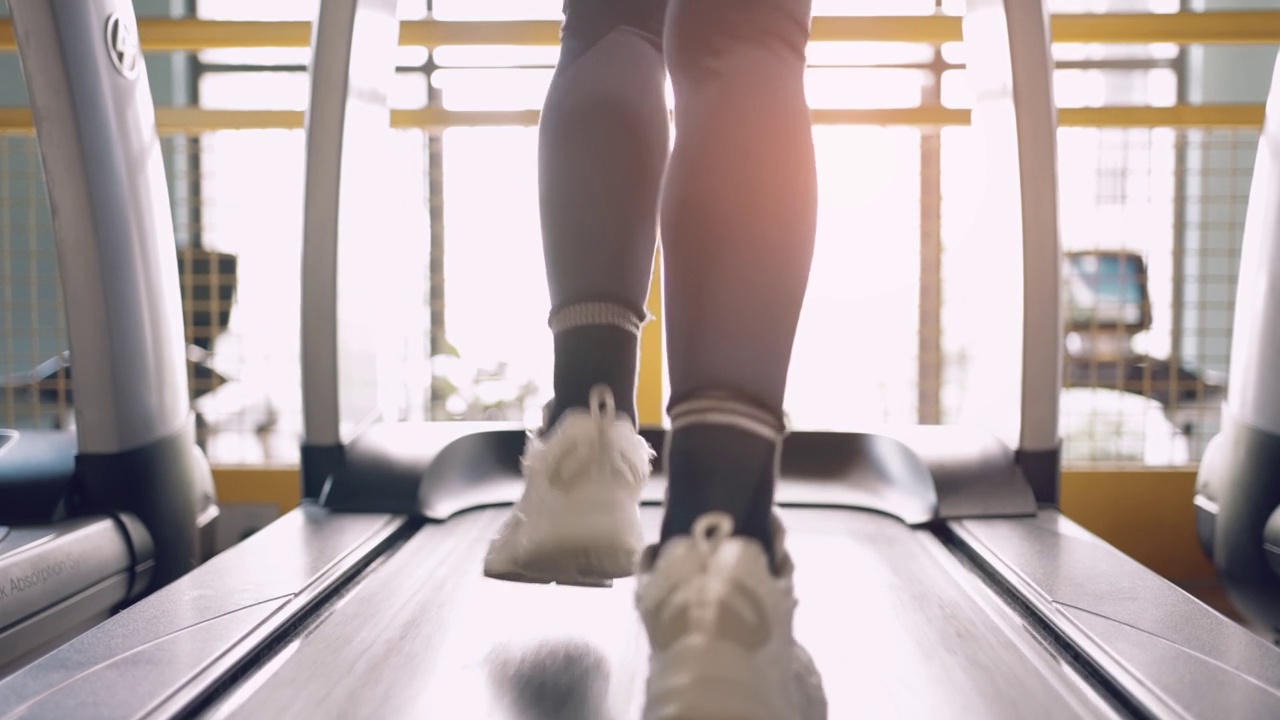在健身房的跑步机上跑步的女人的腿视频素材