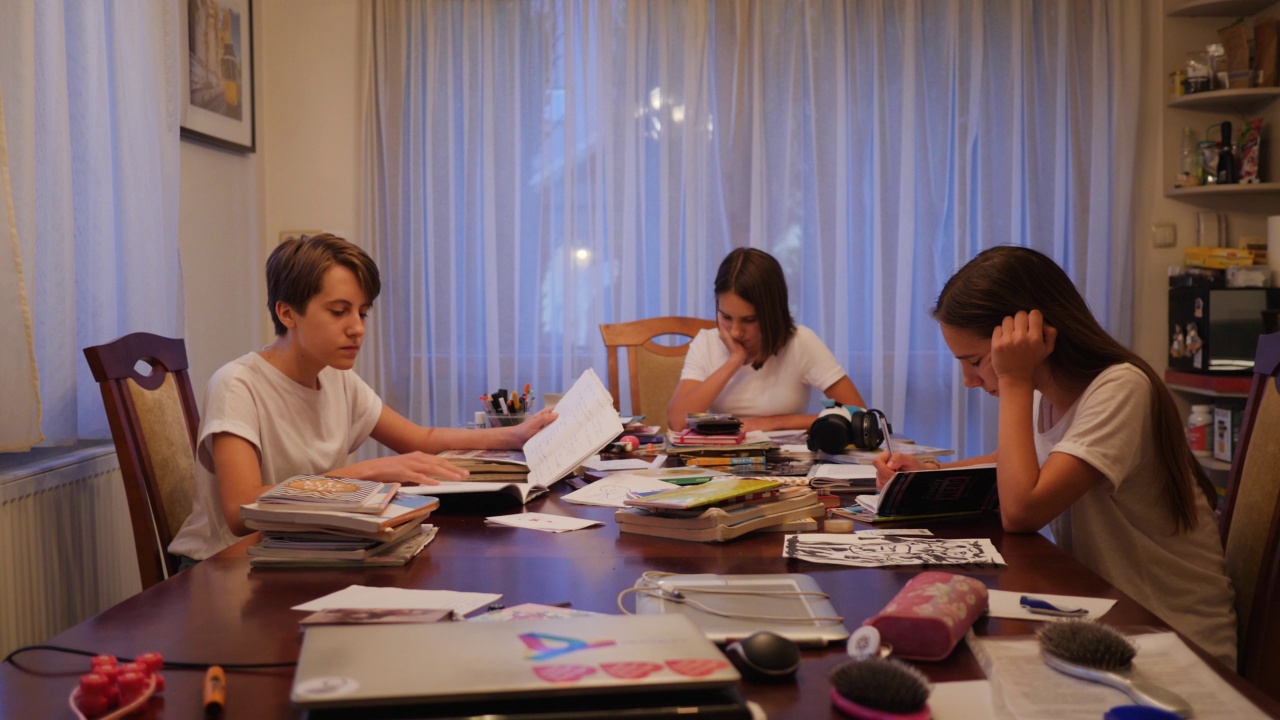 十几岁的女孩三胞胎姐妹在家里的餐厅坐在一个大桌子做家庭作业准备在晚上上学视频下载