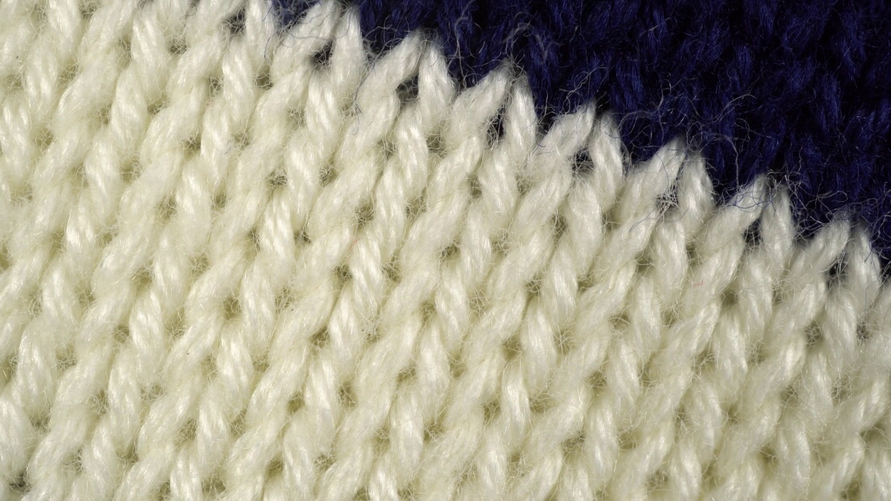 针织毛衣质地的幻灯片。慢动作宏针织服装由蓝色和白色的线。极端的宏。视频素材