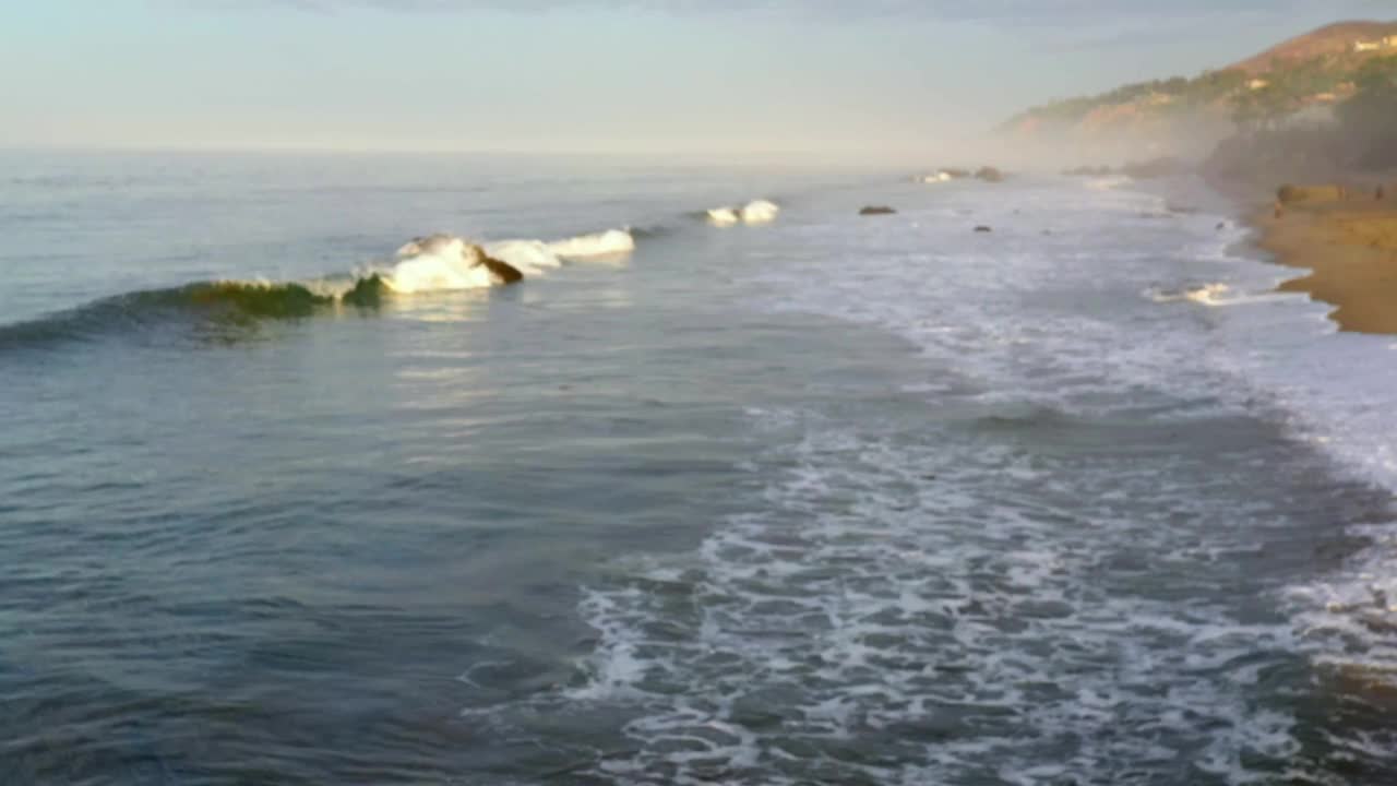 4K无人机库存视频的海滩马里布海滩北部的海浪撞在岩石上视频素材