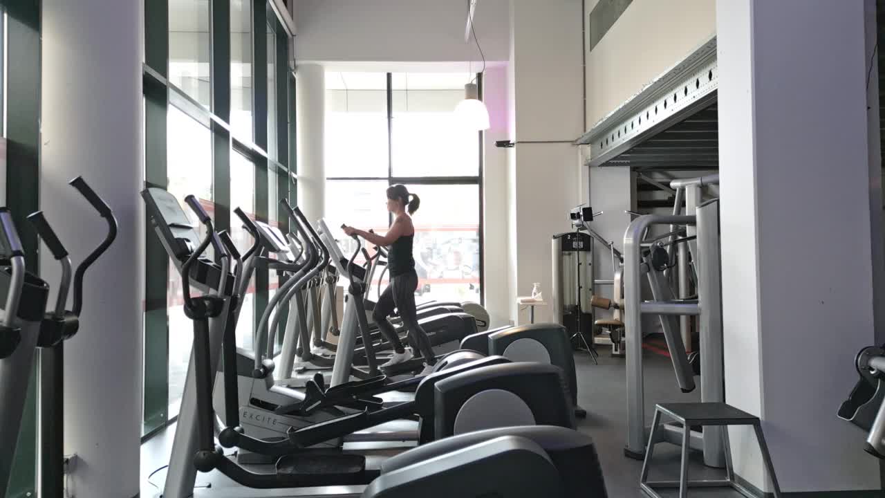 年轻的日本女子在健身房的椭圆机上锻炼视频下载