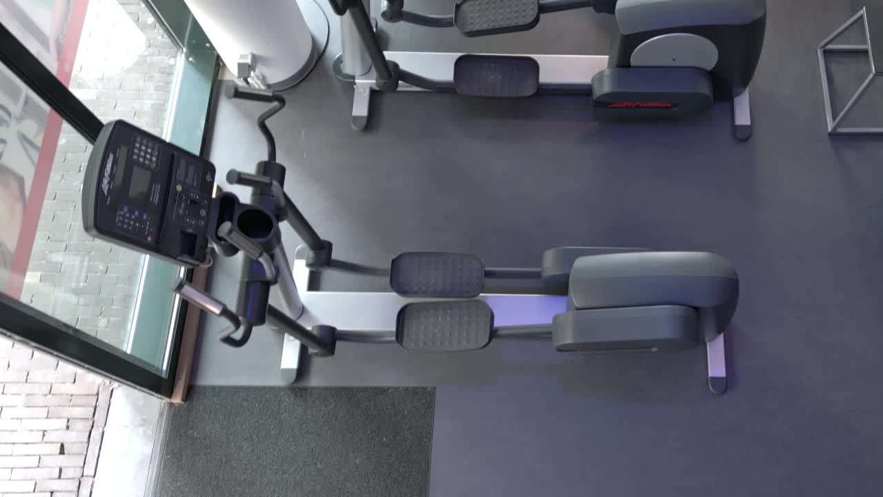 年轻的日本女子在健身房的椭圆机上锻炼视频素材