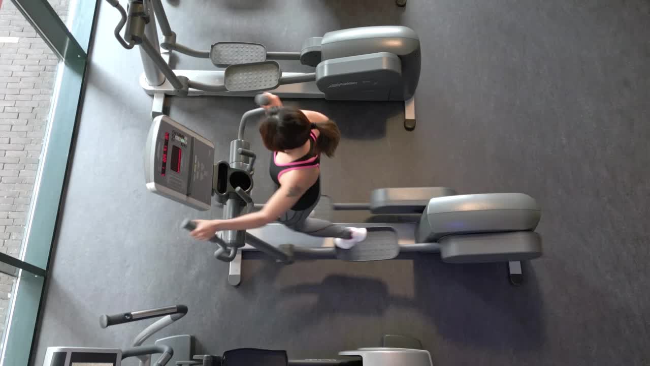 年轻的日本女子在健身房的椭圆机上锻炼视频素材