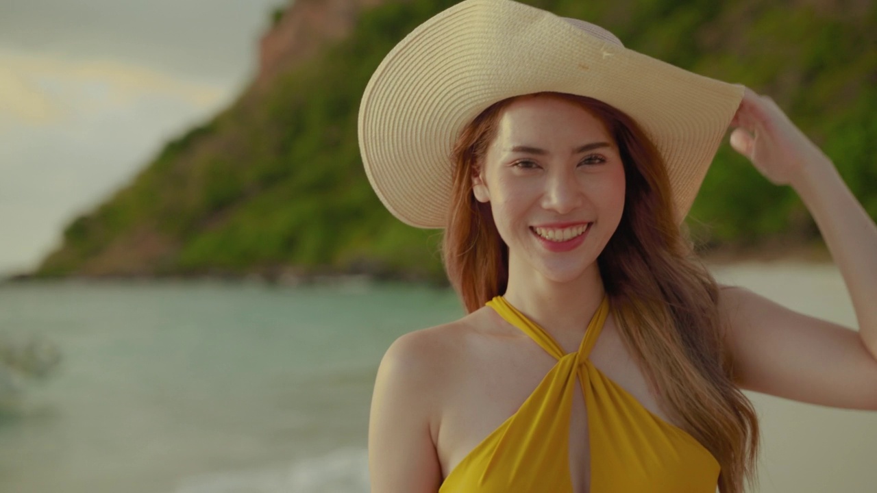 傍晚夕阳西下，美丽的亚洲女孩头戴墨西哥宽边帽，走在海滩上度假，理念自由、旅行、冒险。视频下载