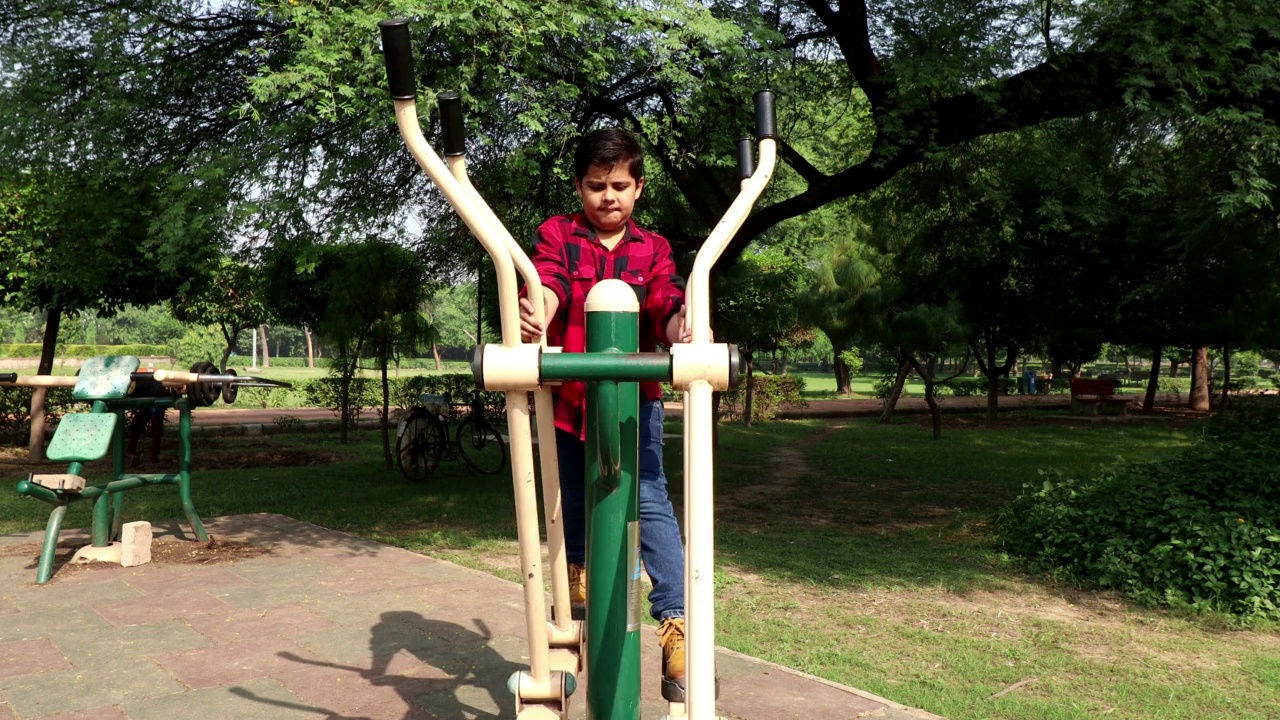 一名小学儿童在公园户外的健康步行者健身机上锻炼视频下载