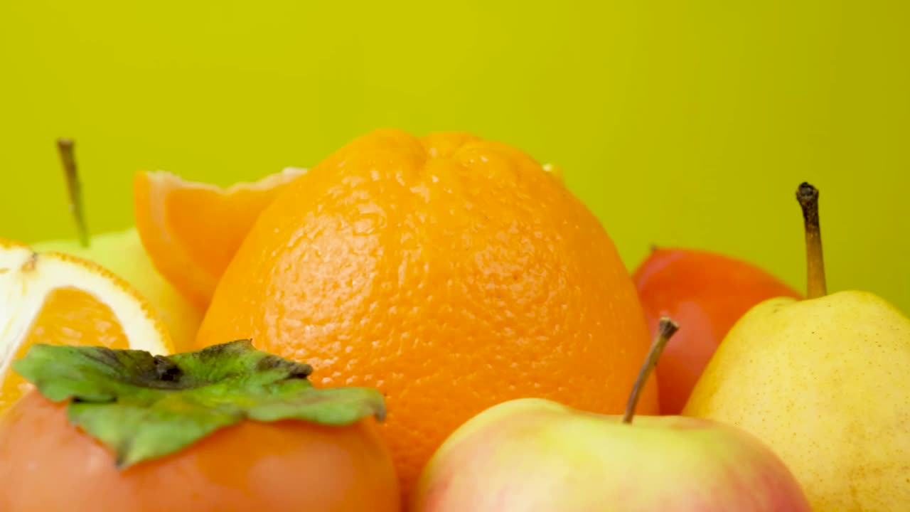 橙色和黄色的水果——以黄色为背景的苹果、柿子、梨和橙子视频下载