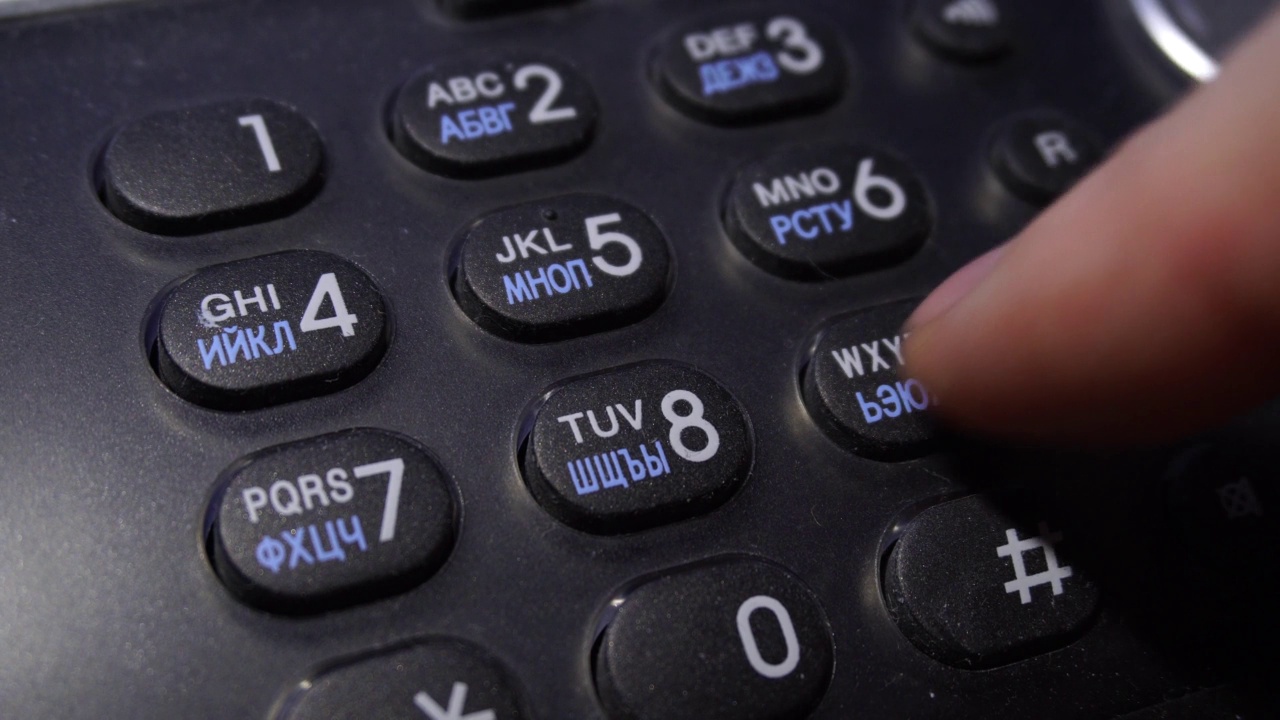 一个老式模拟电话上的数字拨号按钮的特写。用黑色的电话打号码，手指按数字键。视频素材