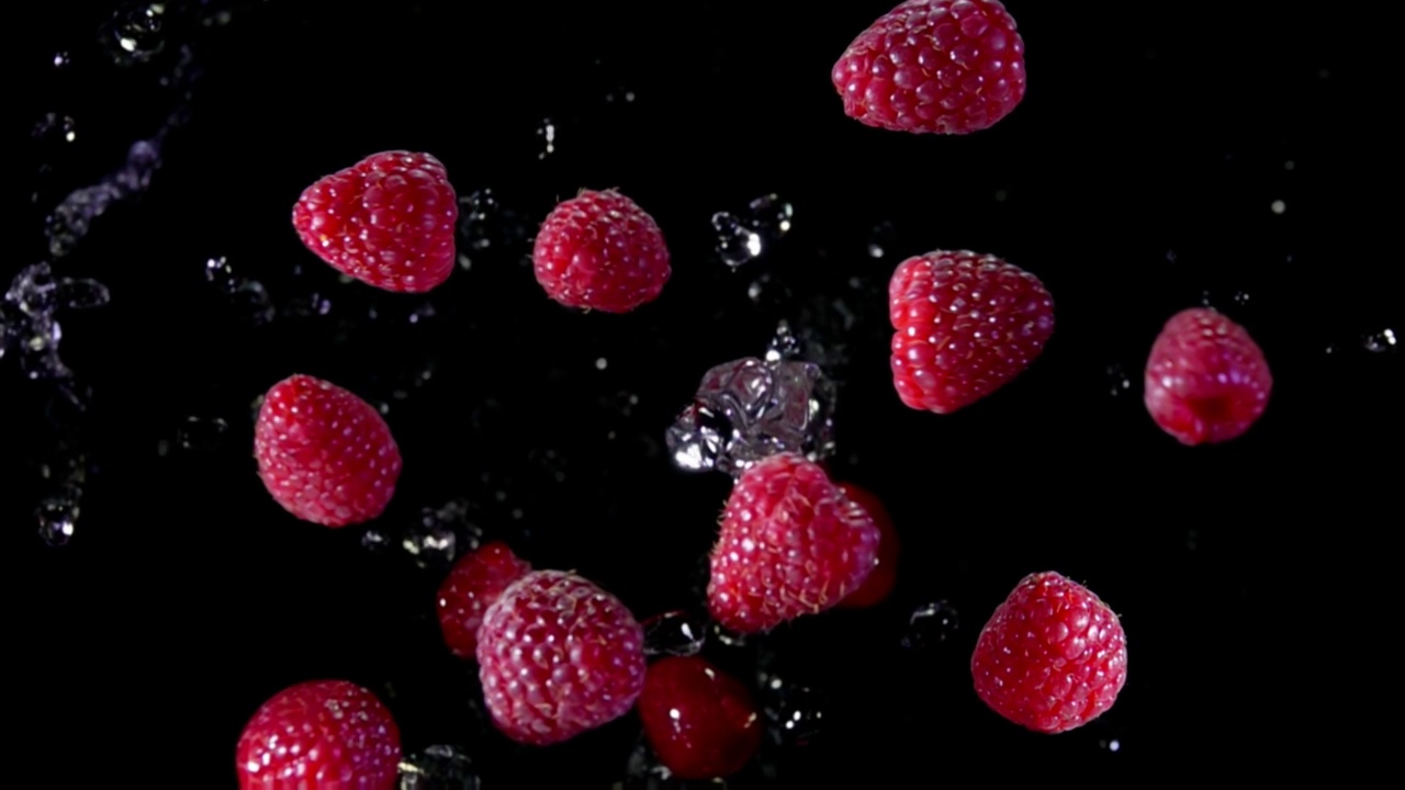 多汁的红色覆盆子在黑色背景上溅起水花视频下载