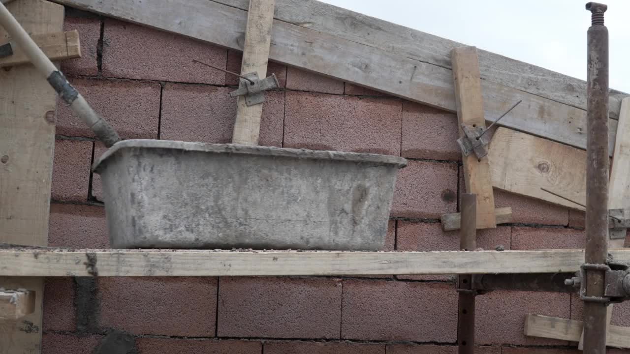 工地中段无名男子手持铁锹将水泥混凝土浇筑在建筑墙面上视频素材