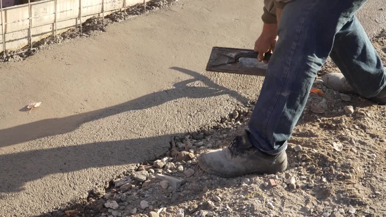 中段不明男子手持铁锹，从工地推车上往地面建筑路面上浇筑水泥混凝土视频素材