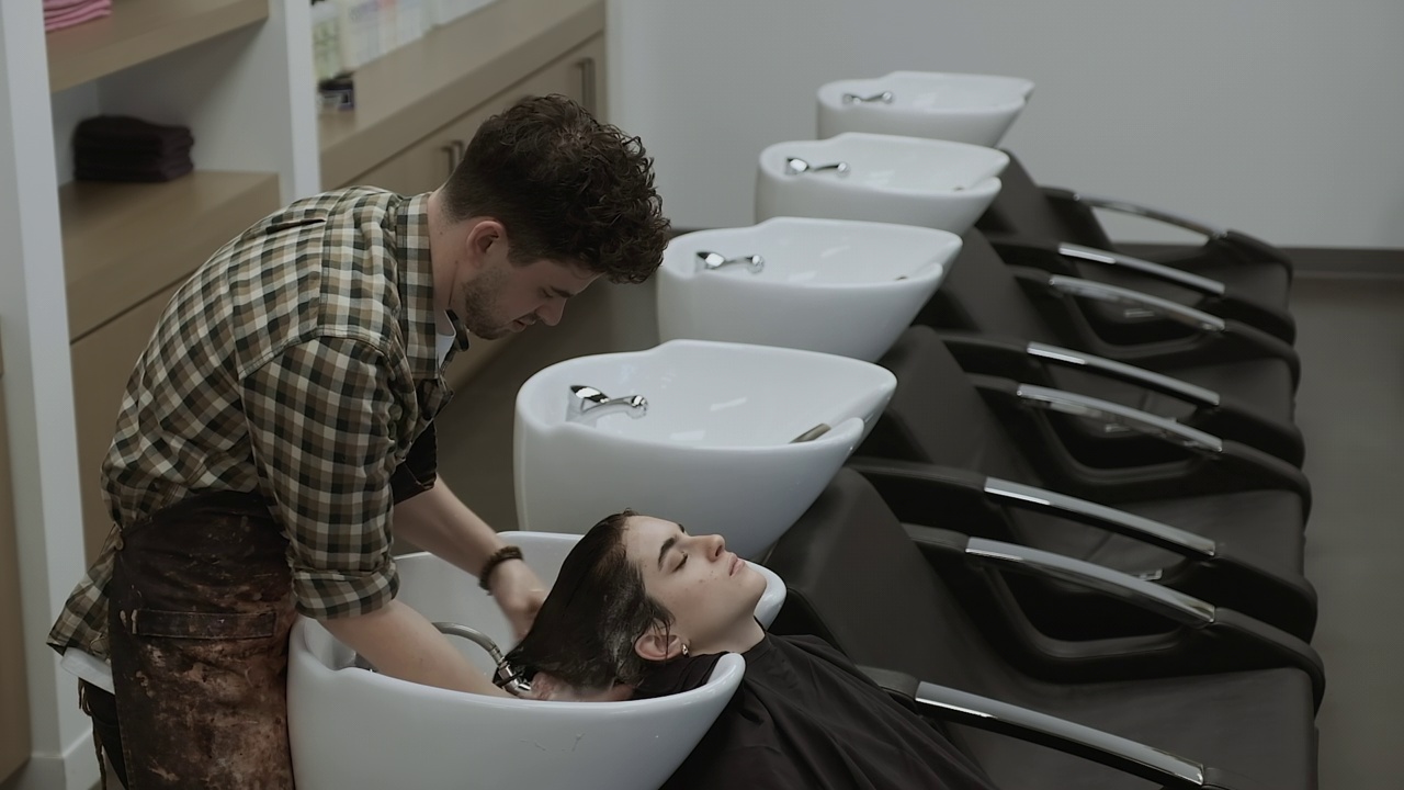 发型师在发廊冲洗女人头发上的洗发水视频下载