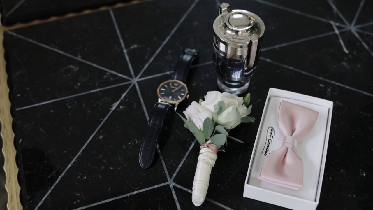 手表、盒子里的领结、香水和桌子上的扣眼的特写视频下载