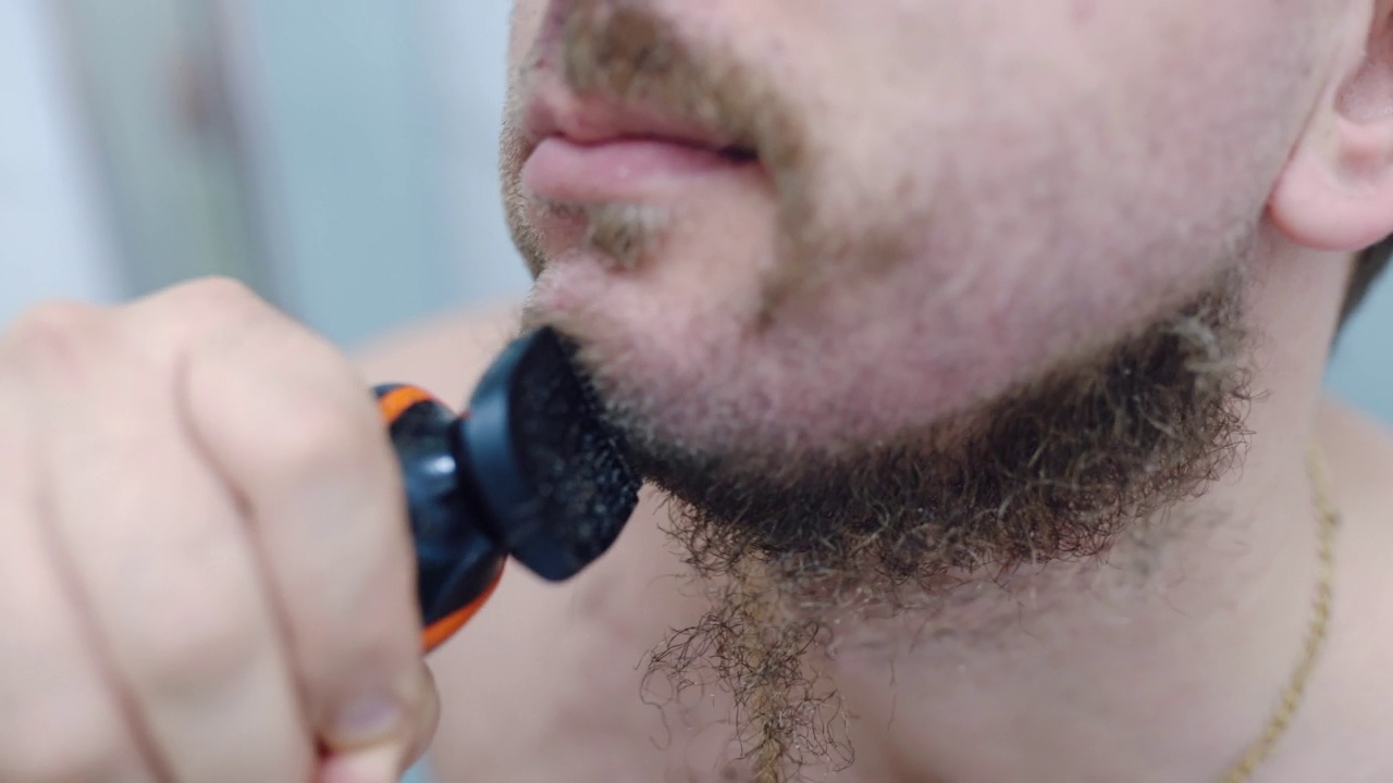 帅哥在浴室做日常美容，男人在镜子前用电动修剪器剃胡子。男性剃须，日常男士的护肤理念视频素材