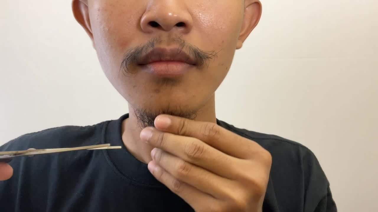 一个男人用剪刀剪胡子。男性保健视频下载