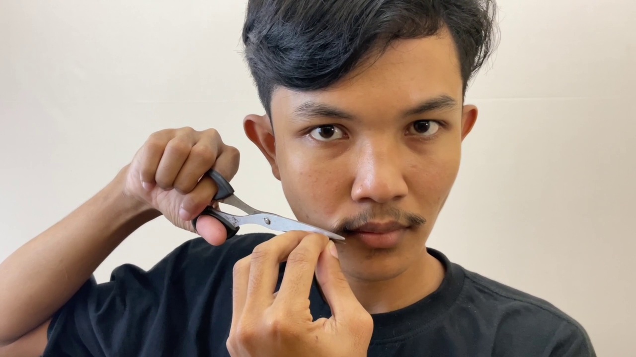 一个男人用剪刀剪他的胡子。男性保健视频素材