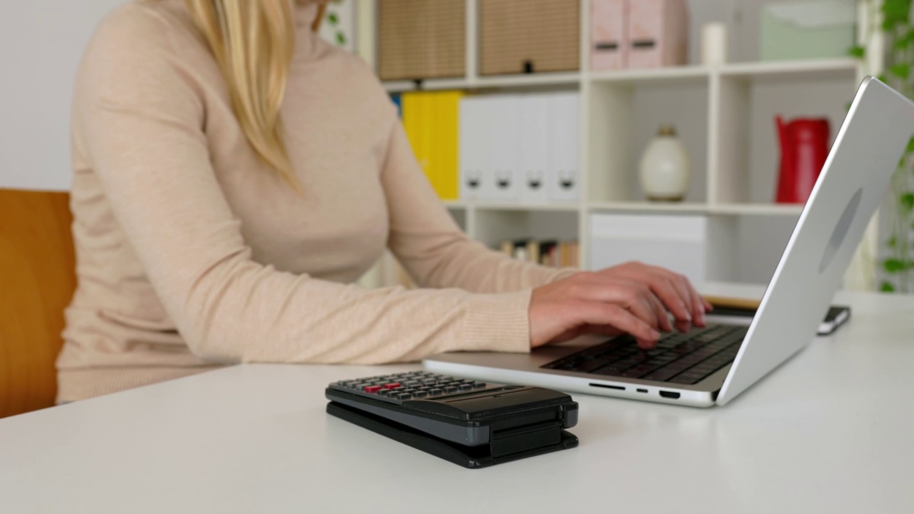 年轻的女商业会计使用计算器和笔记本电脑在家庭办公室视频素材