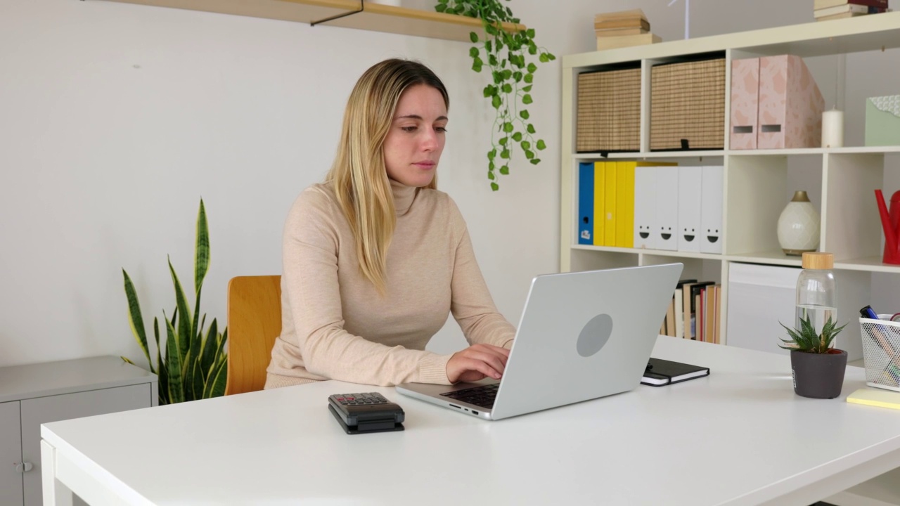 年轻的女商人会计使用计算器和笔记本电脑在家里的办公室视频素材