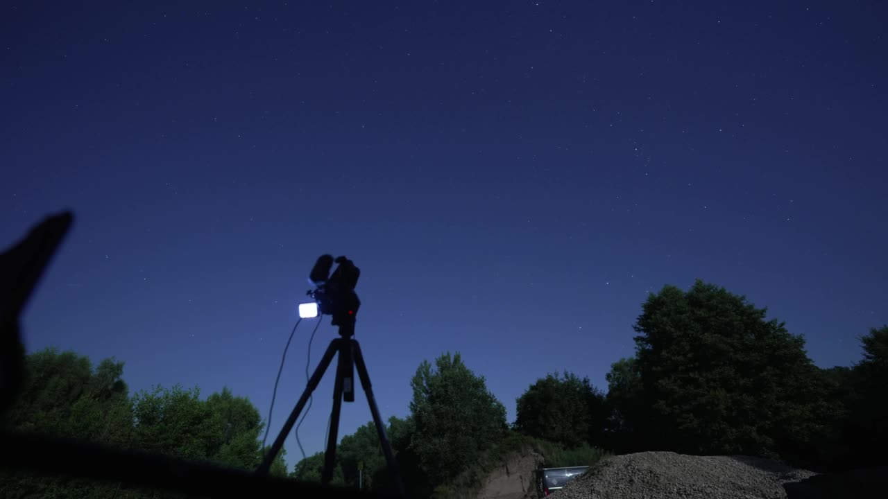一名男子拿着相机拍摄夜晚星空的延时镜头视频下载