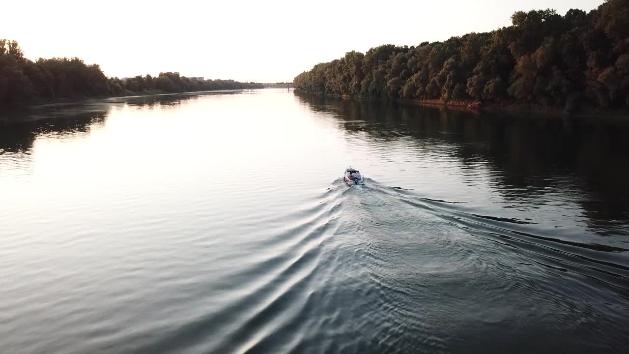 日落时分，小船在平静的河面上巡游的风景视频下载